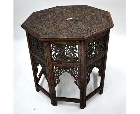 An Anglo-Indian carved and fret panelled table, heavily relief carved overall, the octagonal top on a conforming folding base