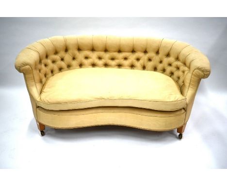 An early 20th century kidney shaped button upholstered sofa raised on short square tapering legs to replacement castors, 160 