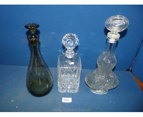 A trio of glass decanters comprising of a square crystal decanter 10 1/4" high; a 20th century light smoky green pear shaped 