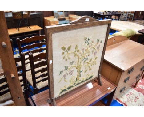 An early 20th Century oak fire screen with embroidered panel