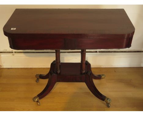 A 19th century mahogany foldover card table on four pillar support and splayed legs on brass hairy claw caps and casters, 74c