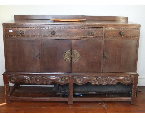 A sideboard with carved decoration having a lower cupboard section surmounted by a line of four drawers, approximately 103 cm