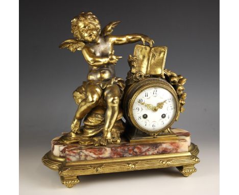 A French gilt metal and rouge marble mantel clock, late 19th century, the case surmounted with a winged cherub upon a rocky o