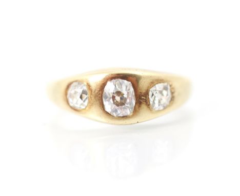 An early 20th century yellow metal and diamond three stone gypsy set ring, the central old cut diamond with smaller old cut d