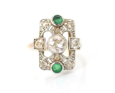 A 20th century diamond and emerald ring, the central old cut diamond in white metal milgrain edge within openwork designed mo