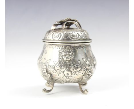 A continental white metal tea caddy, the cast foliate handle upon pull off cover above a bulbous embossed body depicting myth