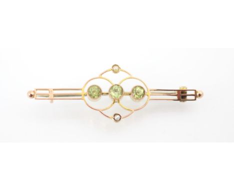 An Edwardian style peridot bar brooch, the three round cut peridots within sinuous mount with split pearl highlights, upon ba
