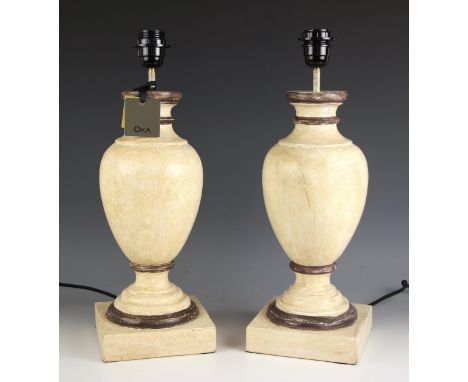 A pair of Oka 'Gela' wooden table lamps, of vase form, painted in ivory shades with brown detail, upon integral plinth bases,