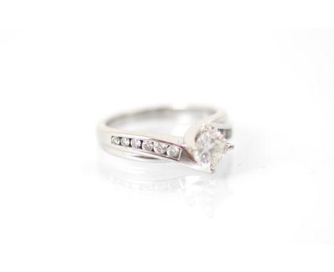 A late 20th century diamond solitaire ring, the round cut diamond in white metal claw setting with smaller round cut diamond 