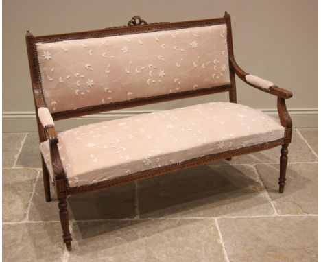 An Edwardian walnut framed sofa, the padded back rest centred with a ribbon tied crest, extending to down swept arms with aca