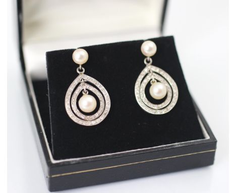 A pair of 20th century style diamond and cultured pearl earrings, the cultured pearl studs suspending three graduated diamond