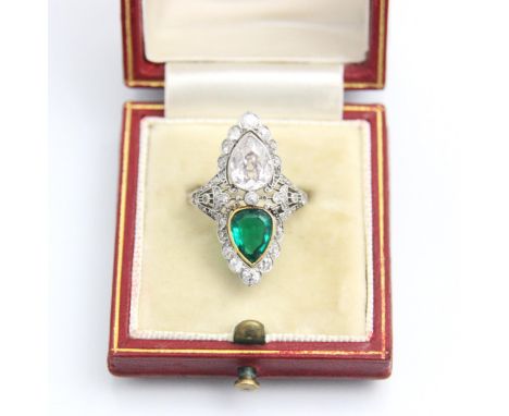 A ‘Belle Epoque’ emerald and diamond set ring, the old cut pear cut diamond within white metal milgrain setting edge, with pe