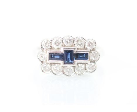 An 18ct white gold sapphire and diamond dress ring, the three baguette cut sapphires within surround of round cut diamonds se