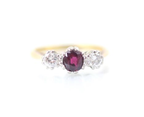 An Edwardian style untested ruby and diamond three stone ring, the oval cut red stone within white metal claw setting, with r