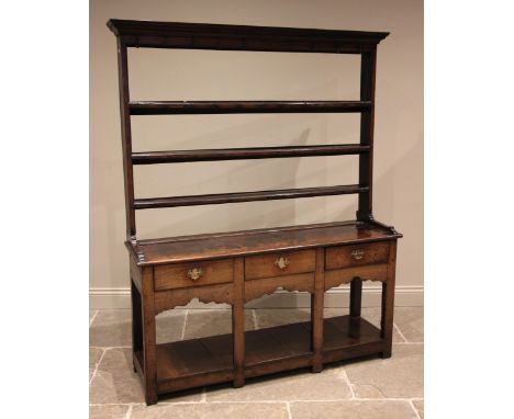 A George III oak dresser, the open plate rack with a moulded cornice over three open shelves, upon the dresser with an arrang