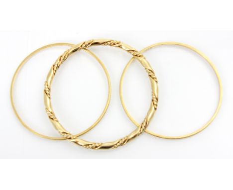 A pair of yellow metal bangles, with applied grooved detail, each engraved ‘22k’ 18gms, with a further gold coloured twist ba