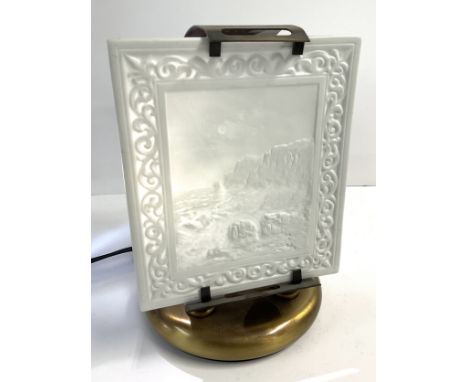 A white porcelain panel with relief decoration, with a view of rough seas on rocks mounted as a table lamp. 14 x 16.5cm