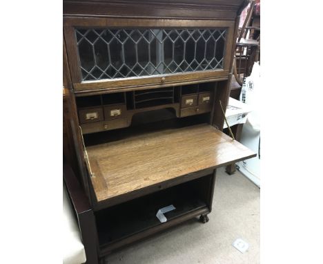 An oak Globewernicke type bookcase with lead light glazed doors a d a fitted bureau. With key lower panel missing.