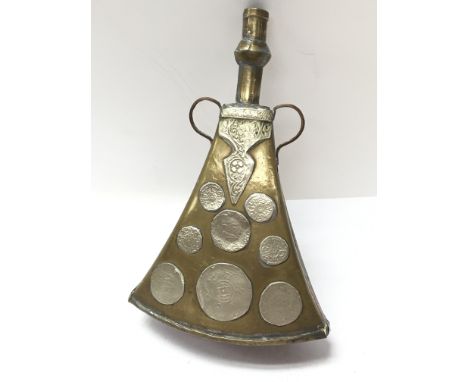 A possibly North African brass powder flask with imitation inlaid coin decoration.