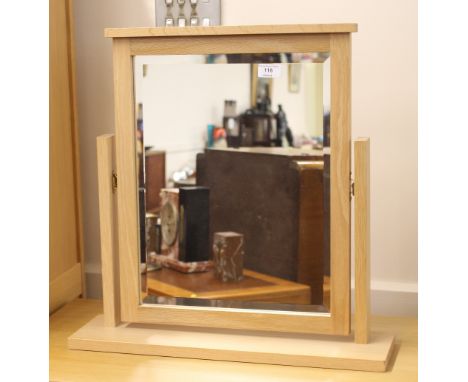A modern light wood bevel edged swing toilet mirror