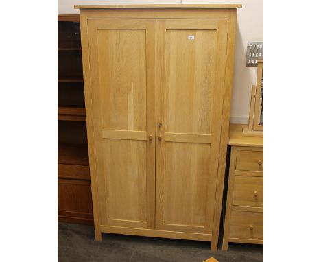 A modern light wood wardrobe, enclosed by a pair of panelled doors, 106cm wide