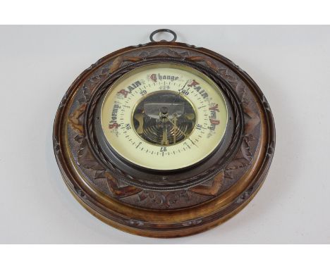 A Victorian aneroid barometer with scale 27 to 31 inches and marker and pointer, in carved circular frame