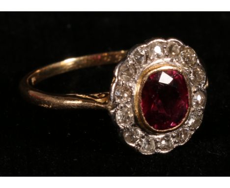 Cluster ring with ruby of almost circular shape surrounded by mixed cut diamonds probably 18ct gold