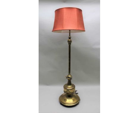 A BRASS STANDARD LAMP, the lower stem with lion mask decoration and swags on a weighted capstan base, 128cm high to light fit