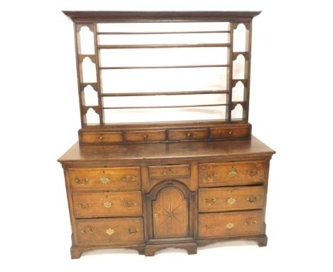 An 18thC oak dresser with moulded corners raised above Delft rack flanked by open shelves with cupboard and draw flanked by s