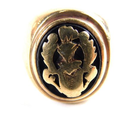 A signet ring, with oval ring head set with black agate, and applied warrior and feather design, on a yellow metal band with 