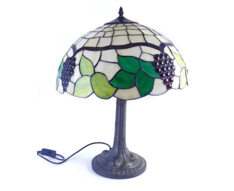 A Tiffany style table lamp, the glass shade set with leaves and berries, 43cm diameter.