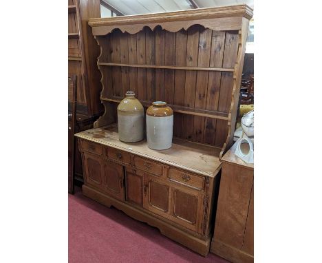 A light oak dresser, having two-tier open plate rack over base fitted with twin frieze drawers, over conforming cupboard door