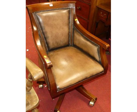 A contemporary mahogany tan leather and further studded swivel desk chair, raised on roller castors, w.57cm