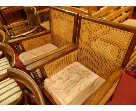 A pair of early 20th century indigenous hardwood and cane bergere chairs, raised on bobbin turned supports with squab cushion