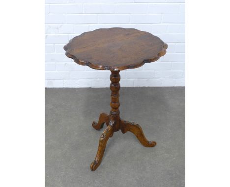 An oak pedestal table, circular top with pie crust edge, on a leaf carved column with tripod legs, 52 x 67cm.