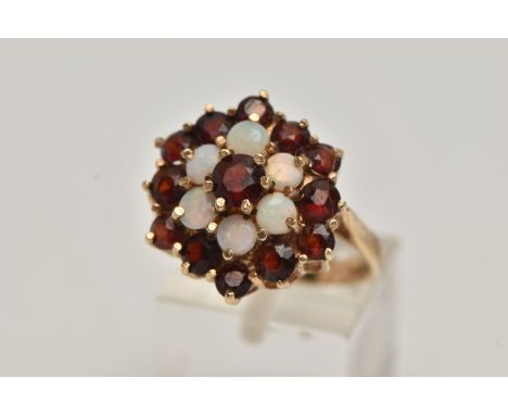 A 9CT GOLD GARNET AND OPAL CLUSTER DRESS RING, comprised of thirteen circular cut garnets and six circular opals prong set in