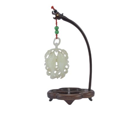 A 19th century Chinese Jade pendant carved as two fish in a framework of reeds and two rings suspended by a fine wooden stand