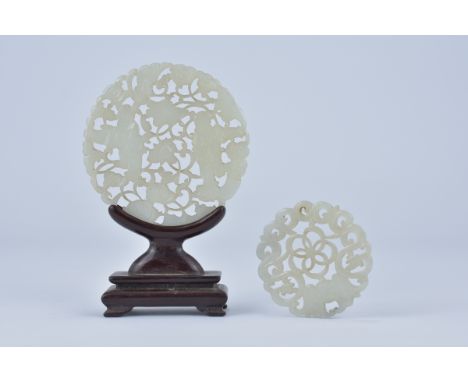 A 19th century Chinese carved circular jade plaque pierced and carved with figures and flowers with wooden stand together wit