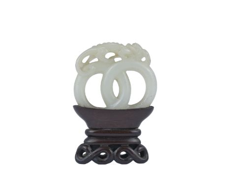 A 19th century Chinese carved White Jade joined rings surmounted by a dragon attached to wooden stand. 7.5cm tall inc stand x