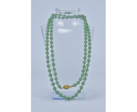 A string of 100 ungraduated pale green Jade Beads in a necklace with gold metal clasps.