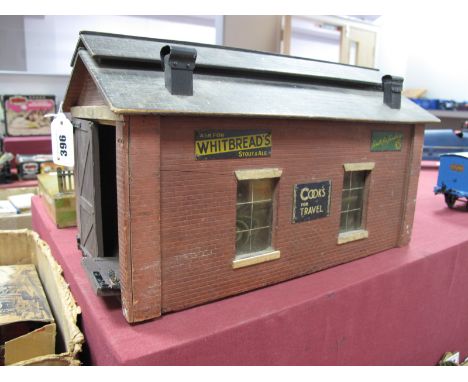 A 1930's 'O' Gauge Wooden Engine Shed for Bassett Lowke, single line, with six tin advertising signs, one door detached.