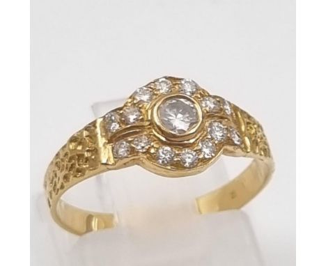 An 18K Yellow Gold Diamond Ring. Central diamond surrounded by 14 smaller diamonds. Size M. 2.1g 