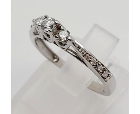 A 9K White Gold Three Diamond Stone Ring. Size M.1.9g. Plus smaller diamonds on shoulders. 