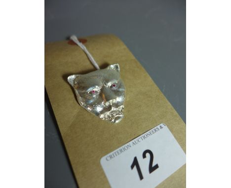 A silver leopard head pendant with ruby eyes. 