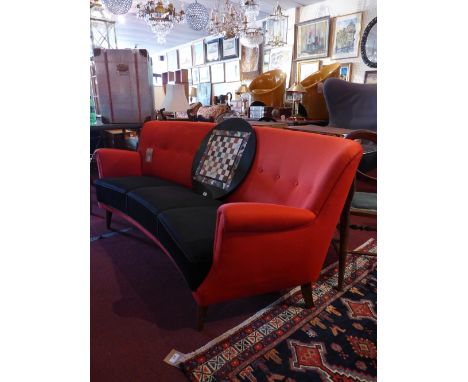 A 1950's Danish three seater sofa upholstered in red, with black seats, having studded back and raised on tapering supports H