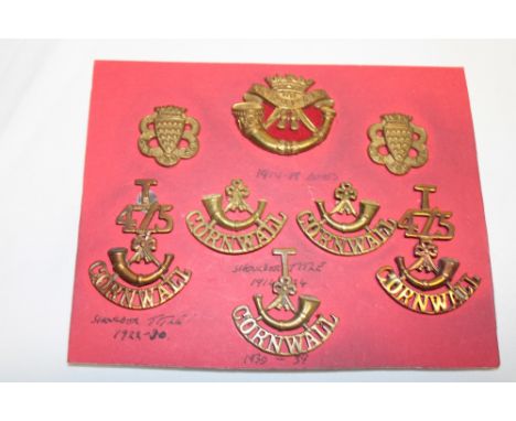 A display of DCLI badges and insignia including 1914-1918 brass issue cap badge, pair of collars, "T/4-5/Bugle/Cornwall" shou