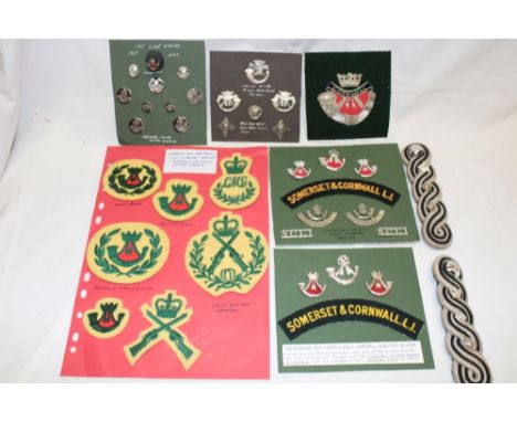 Three displays of Somerset and Cornwall Light Infantry badges and insignia including cap badges, shoulder titles, arm badges 