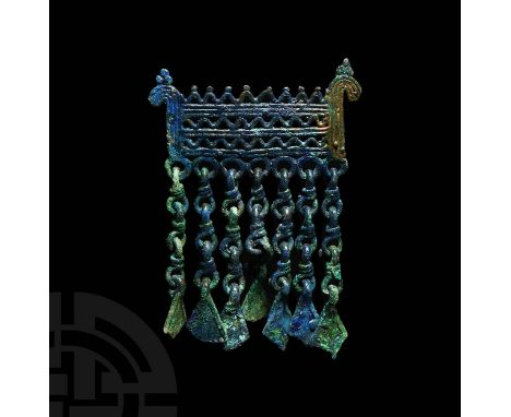 10th-12th century AD. A bronze pendant with openwork rectangular body with stylised horse head terminals, horizontal rows of 