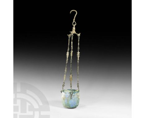 2nd-4th century AD. A glass U-shaped lamp with D-section body and rolled rim, three 'white' opaque glass masks applied around