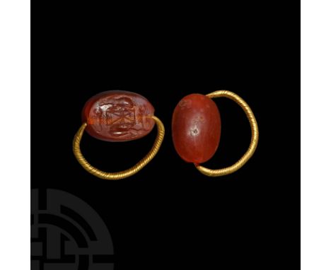 6th-4th century BC. A gold ring with tapering round-section hoop with faux twisted wire design, carnelian swivel scaraboid wi